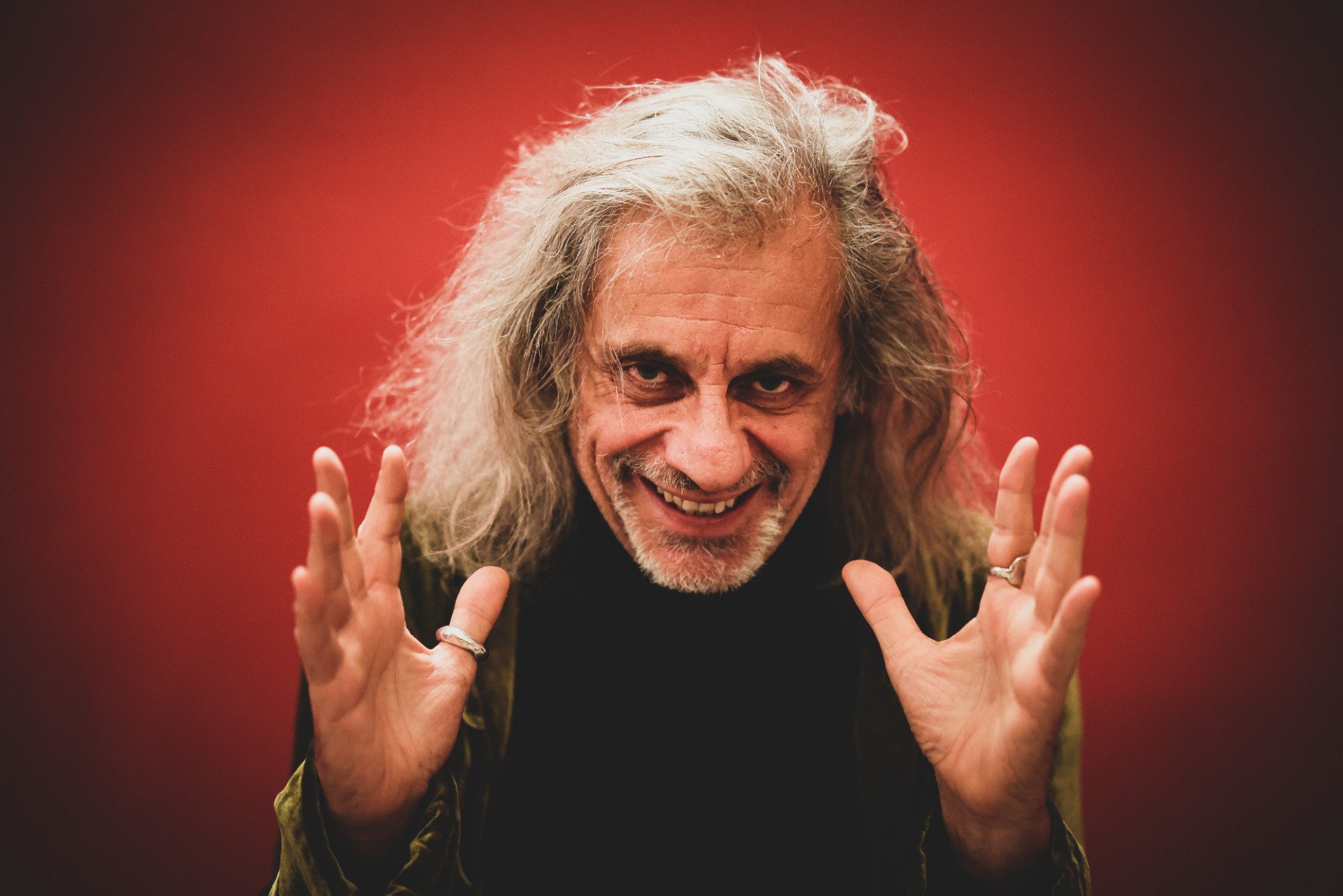 Su sfondo rosso, Alessandro Bergonzoni sorride.