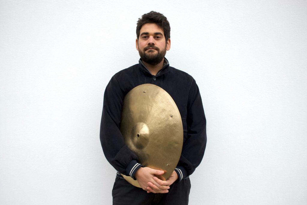 Daniele Patton, su sfondo bianco, tiene tra le mani un piatto della batteria.