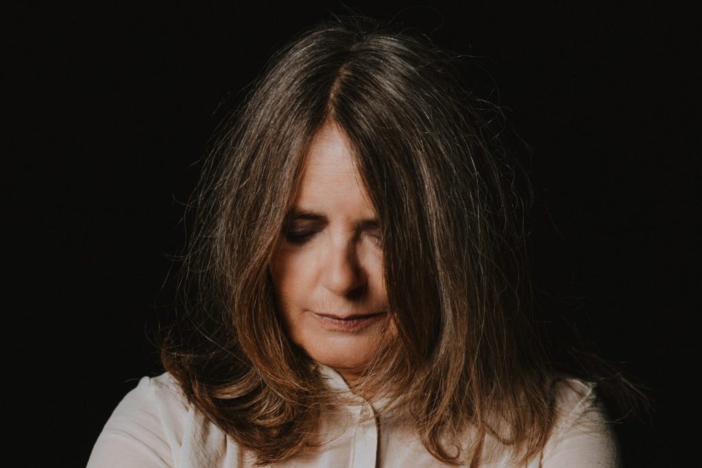 La cantante Nada guarda verso il basso, ha i capelli spostati in avanti che le coprono leggermente il volto.