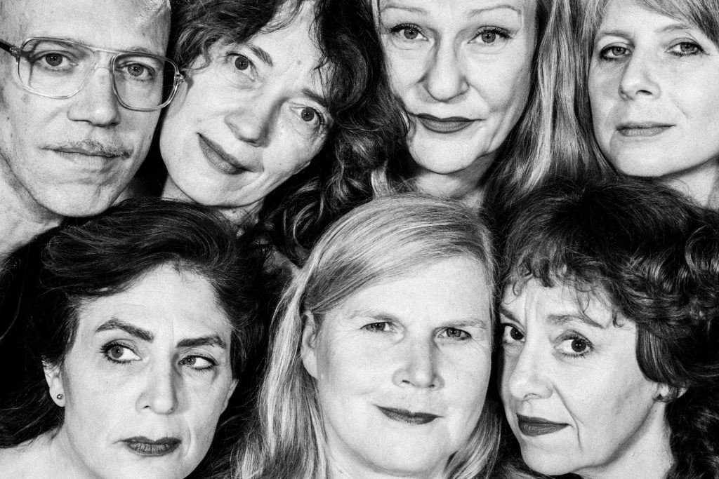 Sette grandi facce di donne e uomini in bianco e nero