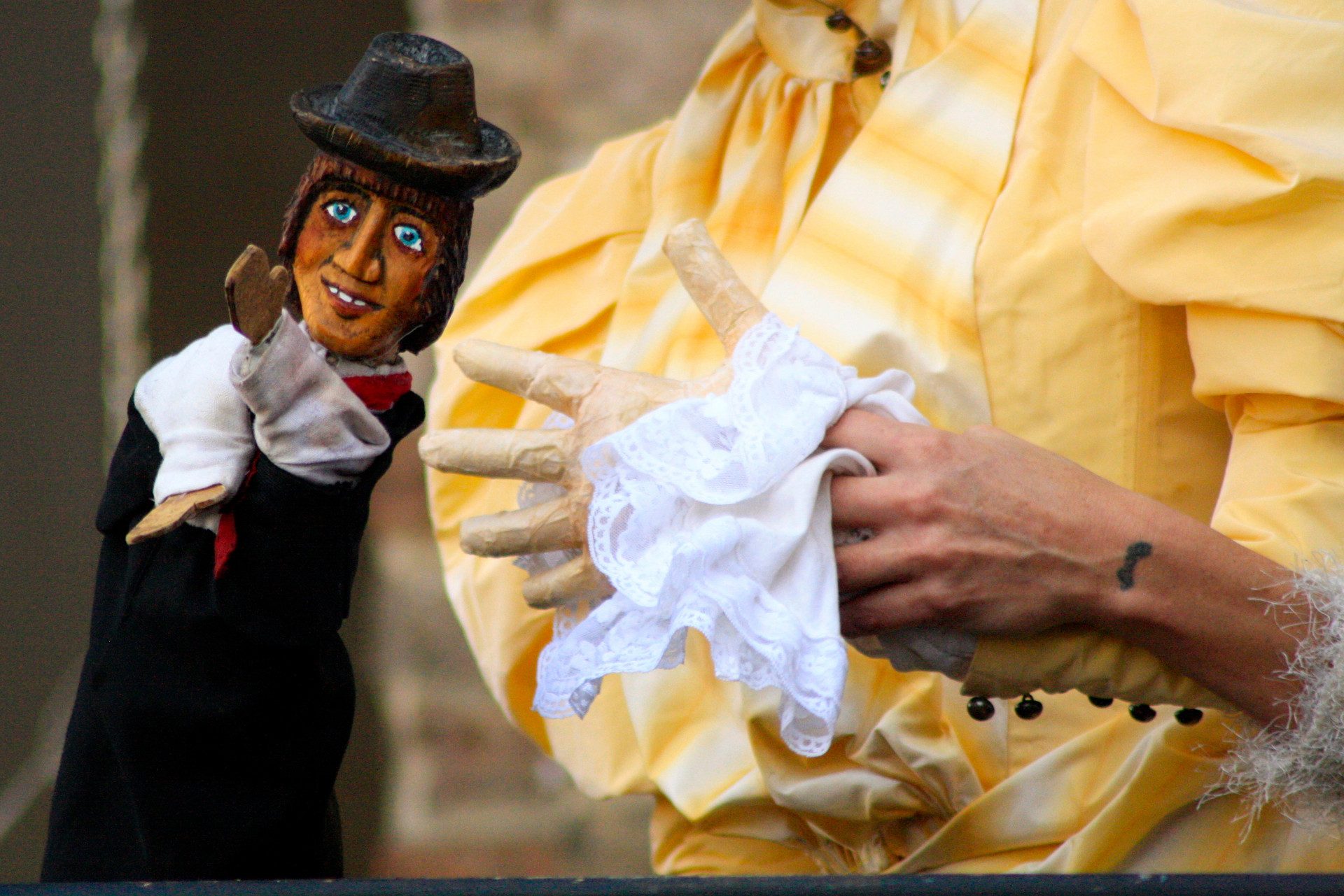 Una marionetta che raffigura un uomo con cappello e le mani del marionettista.