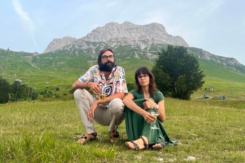 La band Zentaya siede in un prato di montagna e sorseggia degli alcolici.