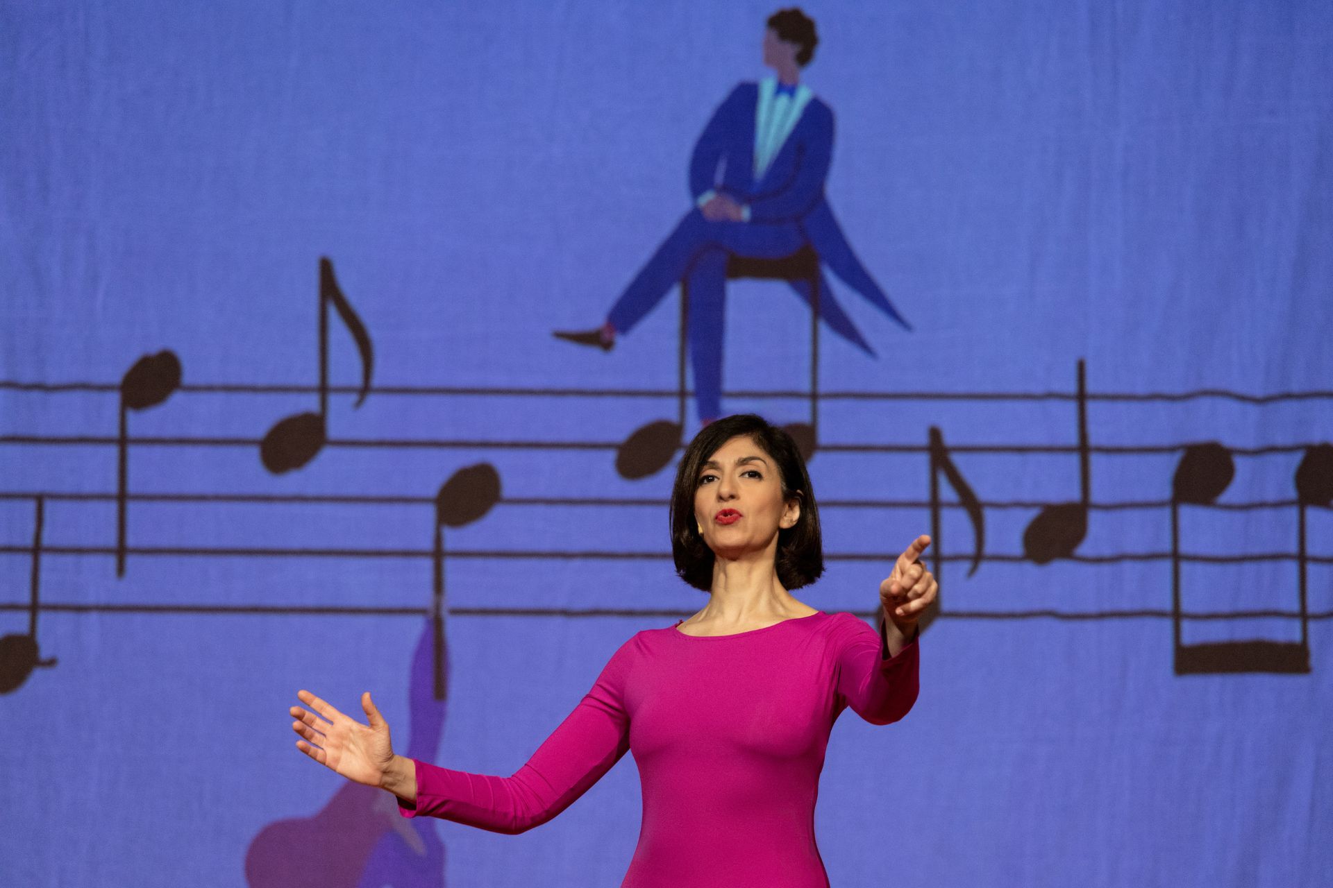 L'attrice Cinzia Spanò a braccia aperte, parlando, vestita con un abito fucsia